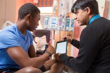 Nirmish Shah, MD, Pediatric Hematology-Oncology Specialist, shows his patient, Clarence Webb, 16, of Fayetteville, how to track his steps, calories and sleep on an app he developed at Duke University Hospital. (Patient release on file)